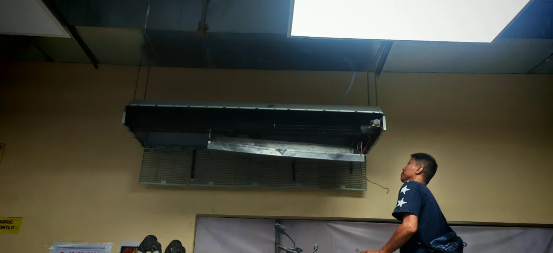 Technician servicing an indoor air conditioning unit
